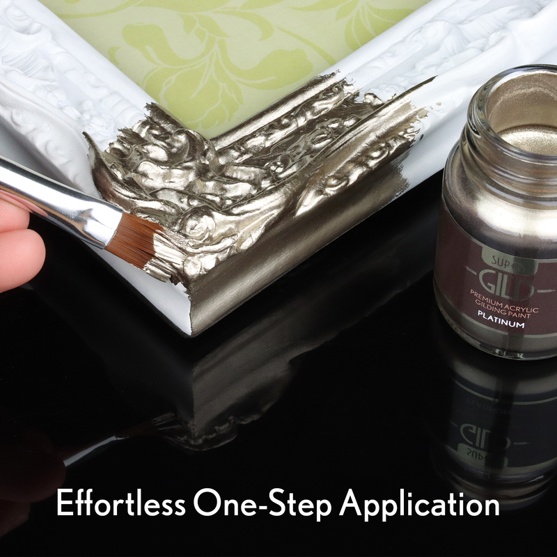 Platinum paintbrush applying metallic paint to a decorative frame with a jar of paint labelled 'GILD'.