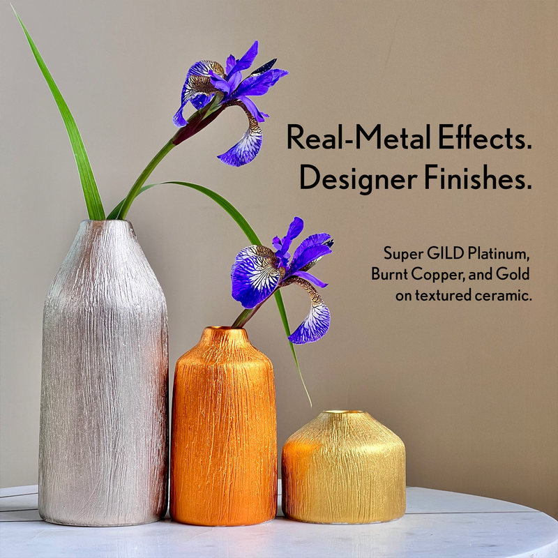 Three textured ceramic vases in platinum, burnt copper, and gold with purple flowers on a neutral background.