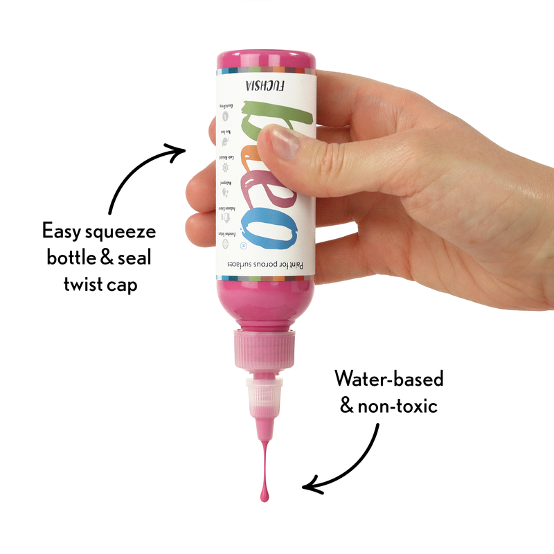 Hand holding a pink water-based paint bottle with text highlighting features on a white background