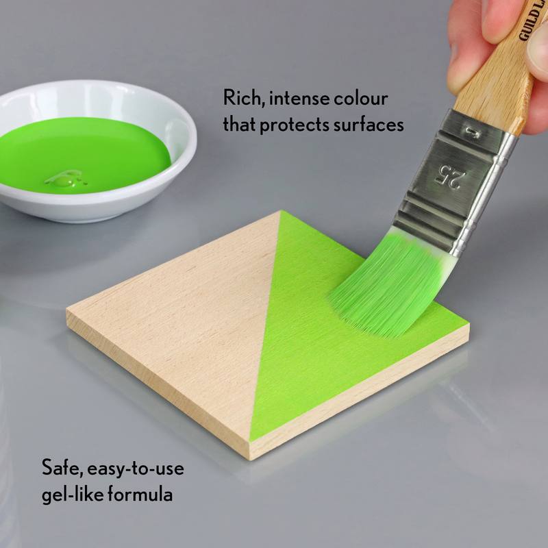 Green gel-like substance being applied to a wooden surface with a brush, on a gray background.