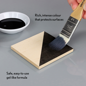 
                      
                        Brush applying black gel-like substance to a triangular wooden block with text about product features.
                      
                    