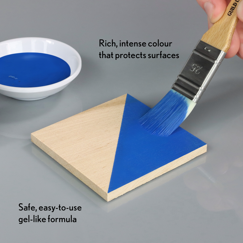 Blue paint being applied to a wooden triangle with a brush, next to a bowl of paint and text describing the product.