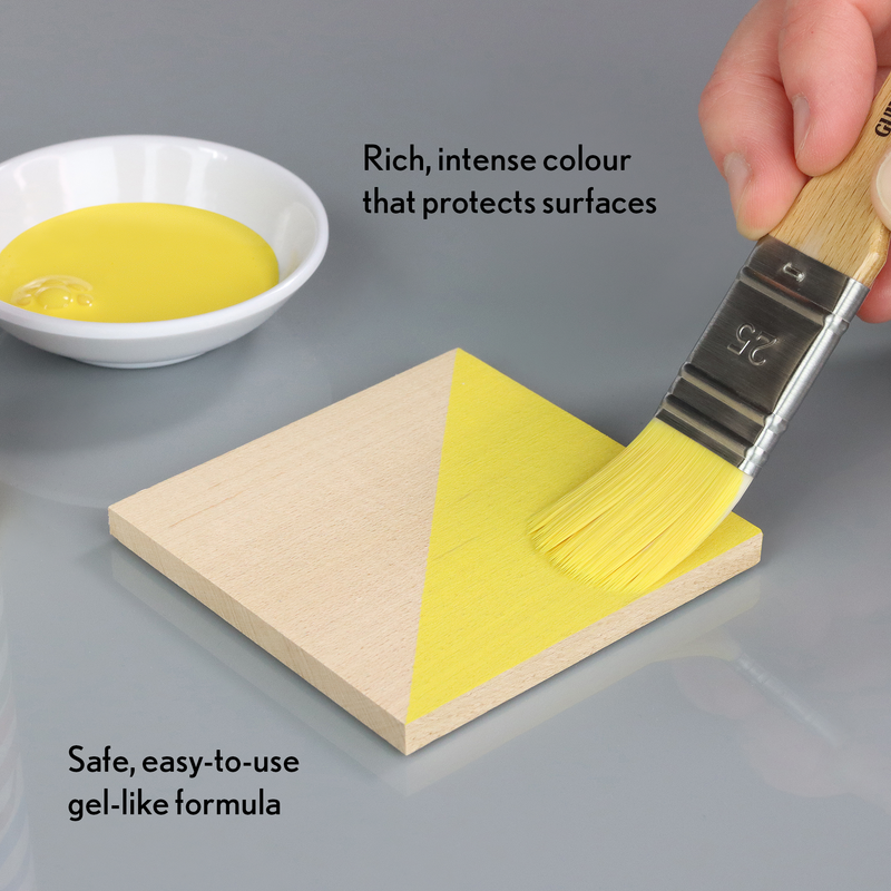 Yellow gel-like substance being applied to a wooden block with a brush, next to a bowl of the gel.