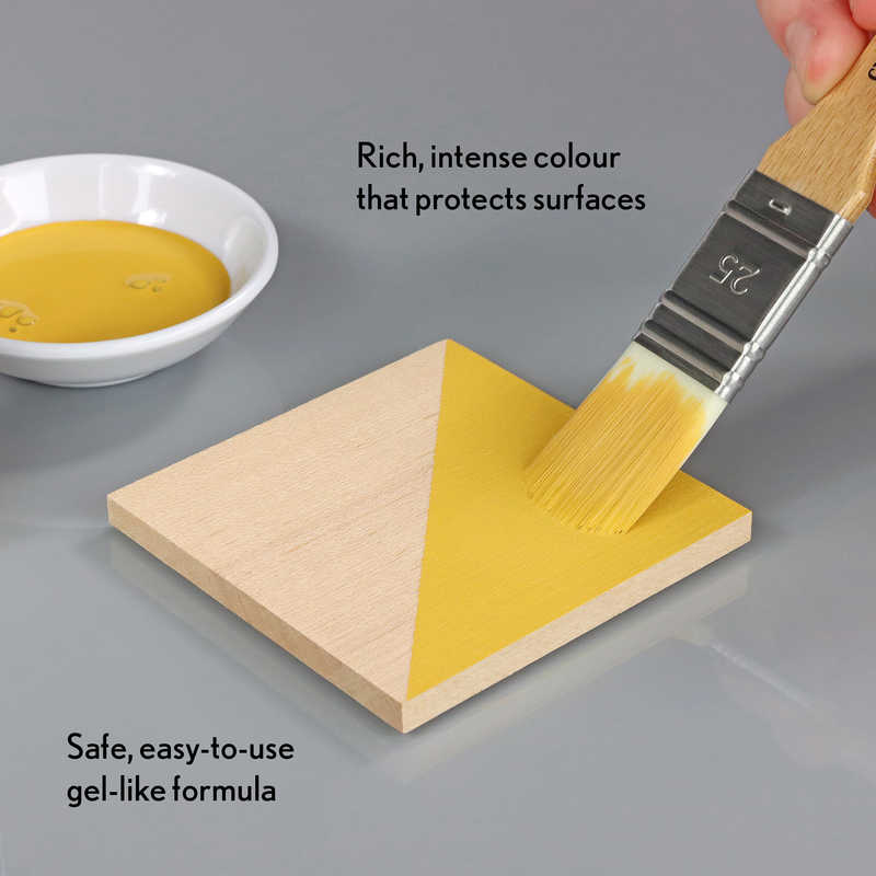 Yellow gel-like substance being applied to a wooden block with a brush, next to a bowl of the gel.