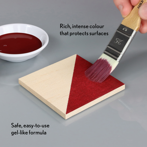 
                      
                        Person applying red paint to a wooden triangle with a brush, next to a bowl of paint.
                      
                    