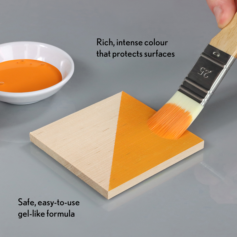 Orange paint being applied to a wooden triangle with a brush, next to a bowl of paint and text describing the product.