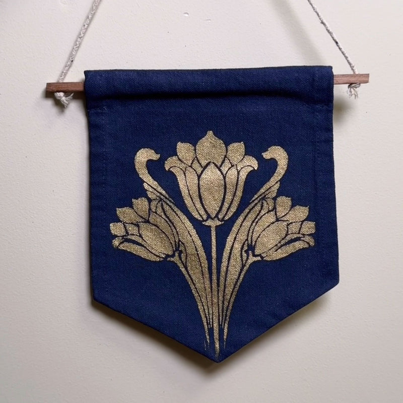 Blue banner with gold floral design hanging on a white wall