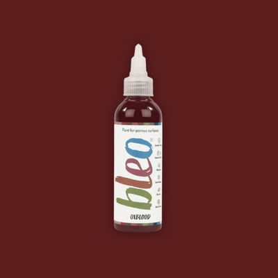Bottle of bleo paint with a white cap on a dark red background