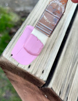 A wooden chair being painted in Bleo Pink