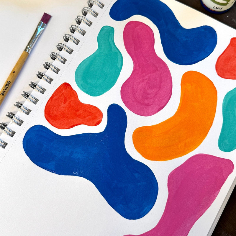 Colourful abstract paint splashes on a notebook page with a paintbrush.