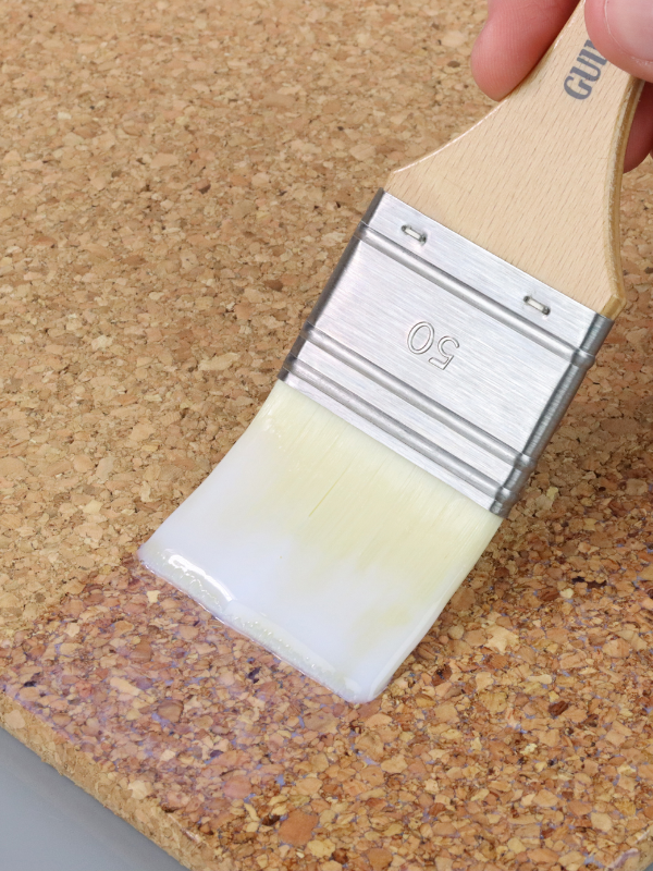 Paintbrush with white paint on a cork surface