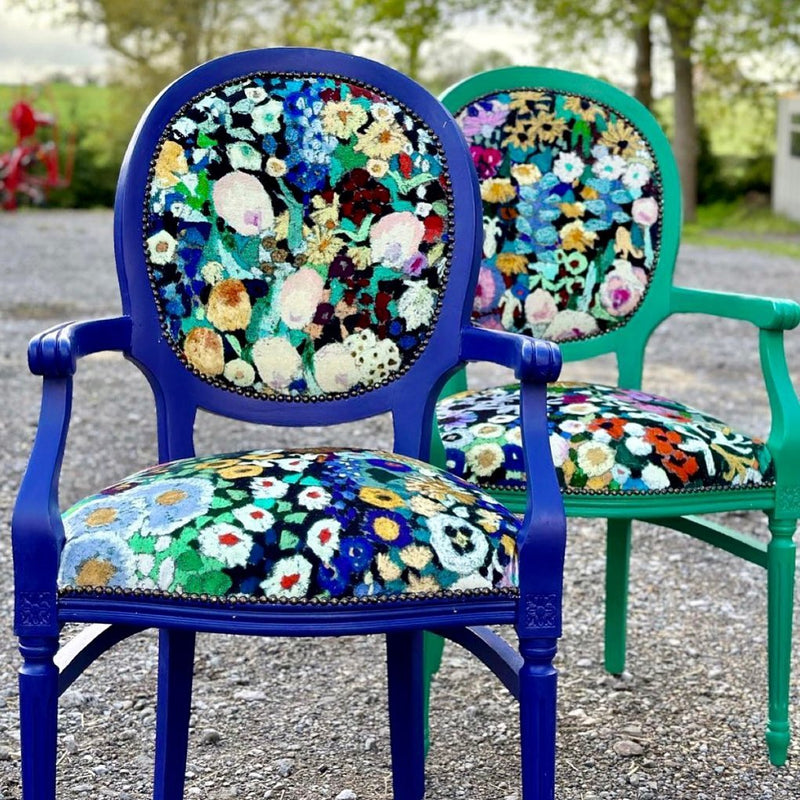 Two chairs with floral-patterned cushions on a gravel surface.