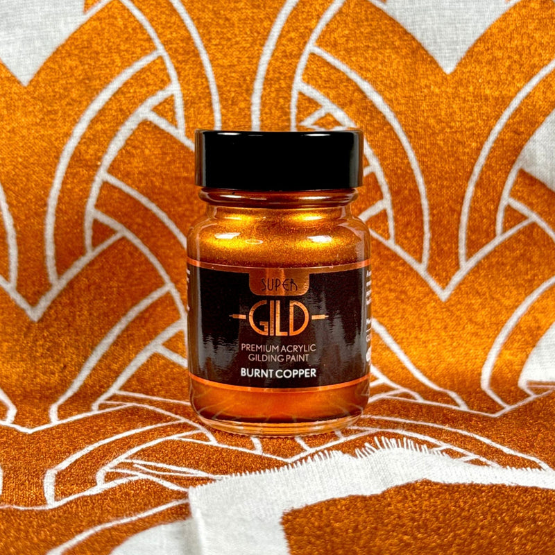 Super Gild acrylic gilding paint bottle on an orange and white patterned background