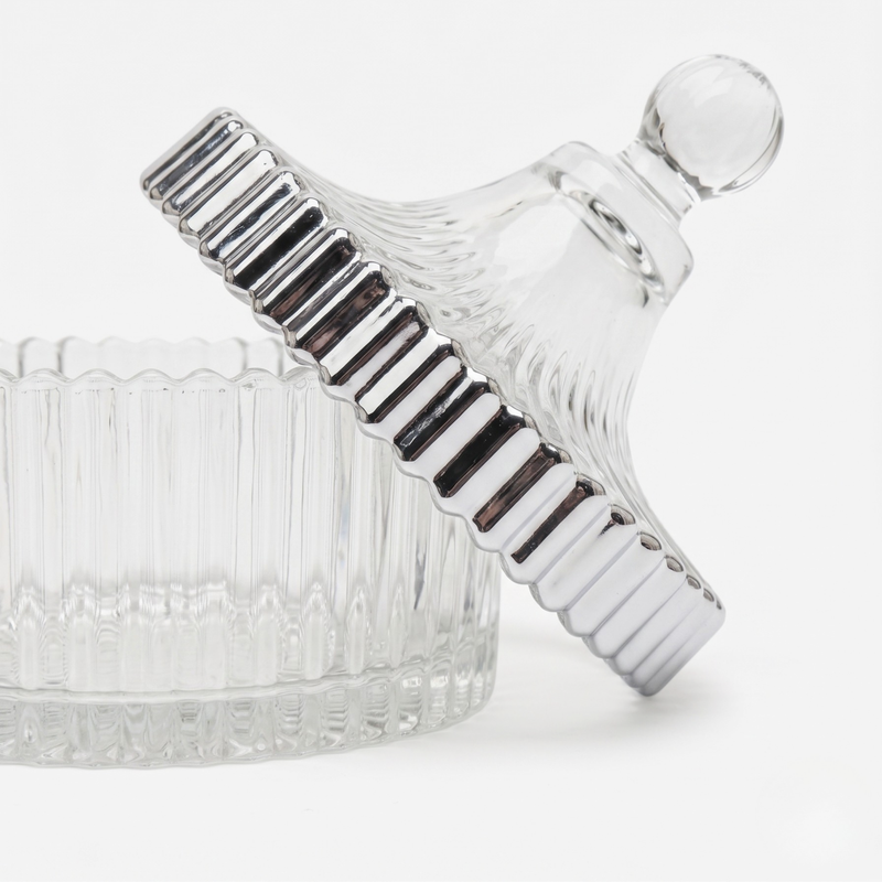 Clear glass trinket jar with chrome painted trim on a white background