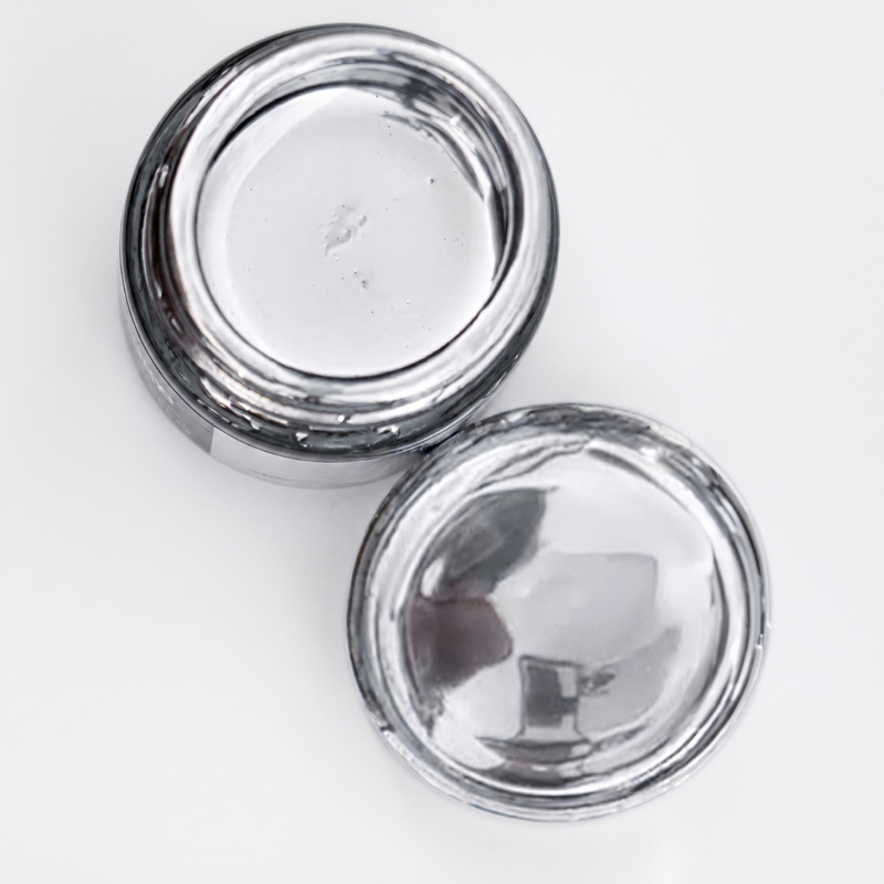 Open jar of metallic chrome mirror silver on a white background