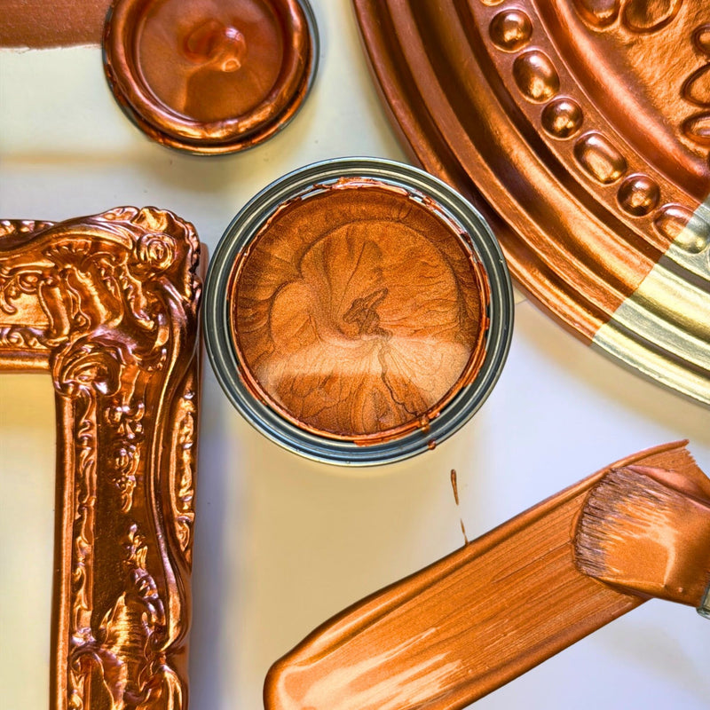 Close-up of decorative copper items including a lid, frame, and tool on a white background.