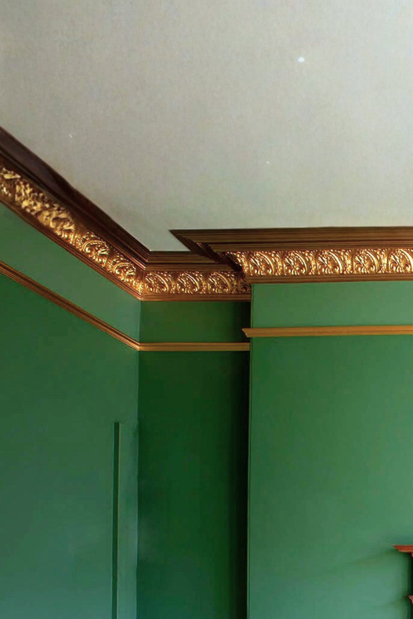 Decorative gold molding on a green wall with a white ceiling