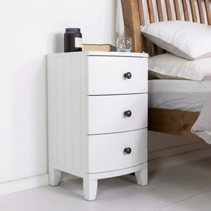 
                      
                        A small side table next to an oak bed with white linen, the drawers are painted in Dover Chalk Jubilee bright white paint
                      
                    