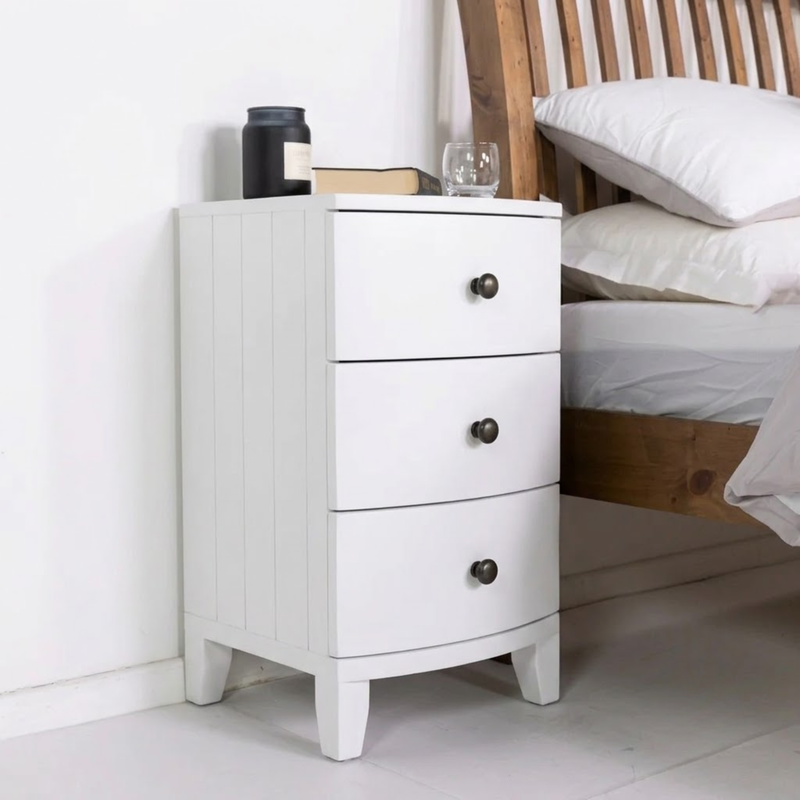 A small side table next to an oak bed with white linen, the drawers are painted in Dover Chalk Jubilee bright white paint