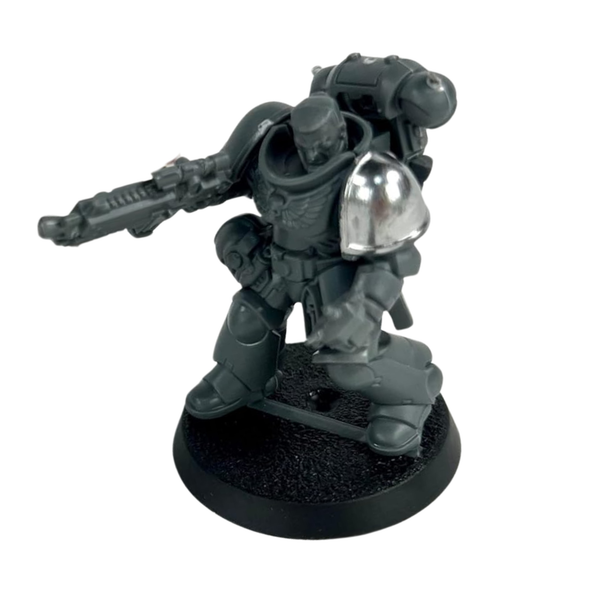 Grey plastic miniature figure with armour and weapon on a white background the shoulder piece is painted in brilliant shiny chrome effect