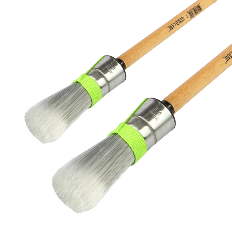 Two paint brushes with wooden handles and metal ferrules on a white background