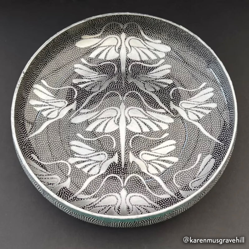 Decorative glass bowl with intricate white floral pattern on a dark background
