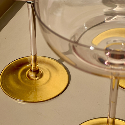 Close-up of a glass with a gold base on a neutral background