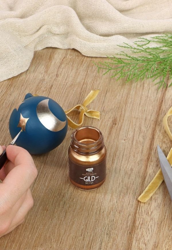 Bottle of Gilding Fluid with a spoon and blue container on a wooden surface