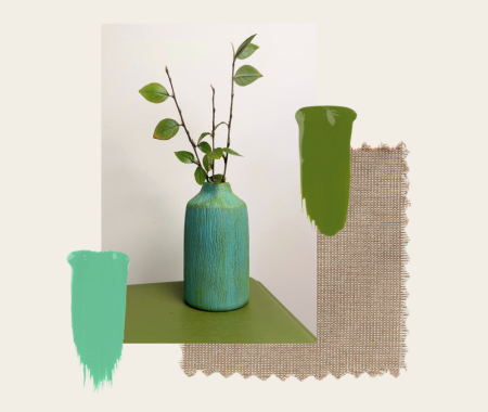 Green vase with plant on a green surface next to fabric swatches