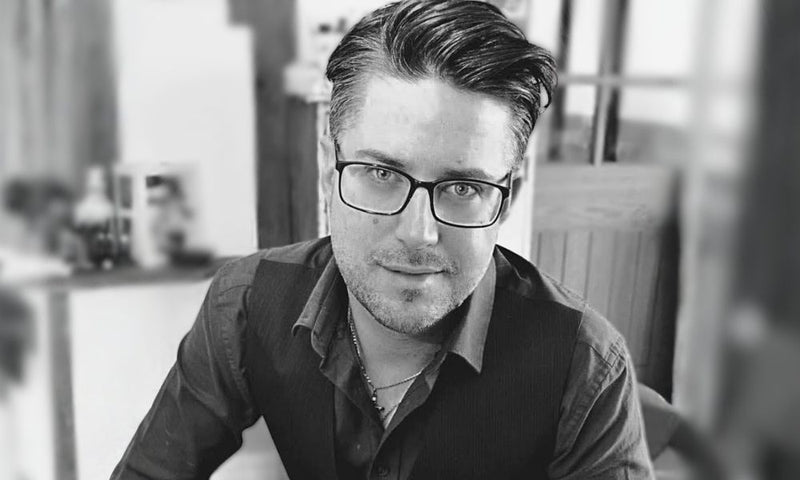 Black and white portrait of a man wearing glasses indoors.