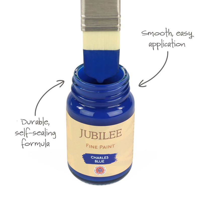 Blue paint being applied with a brush to a bottle labeled 'Jubilee Fine Paint' on a white background.