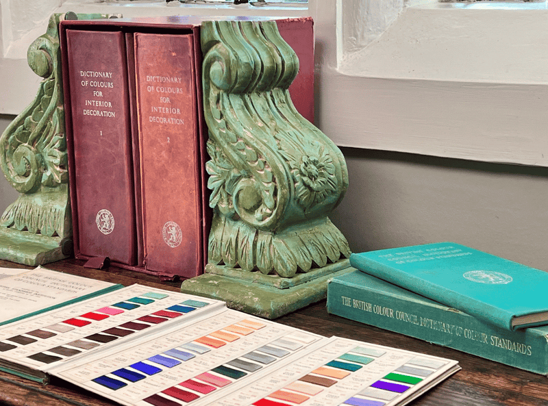 Jubilee colour swatch book open on a rustic surface, showing the range of heritage shades.