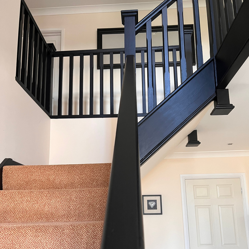 Spiral staircase with black railing in a home interior.