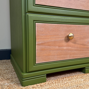 
                      
                        Wooden drawer with green frame and gold handle on a carpeted floor.
                      
                    