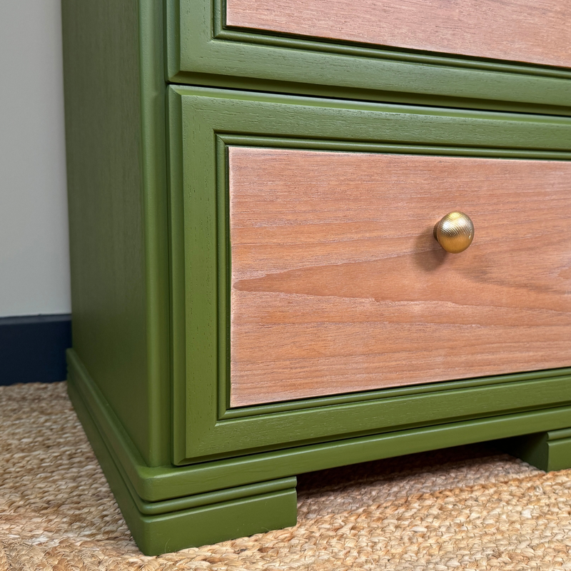 Wooden drawer with green frame and gold handle on a carpeted floor.