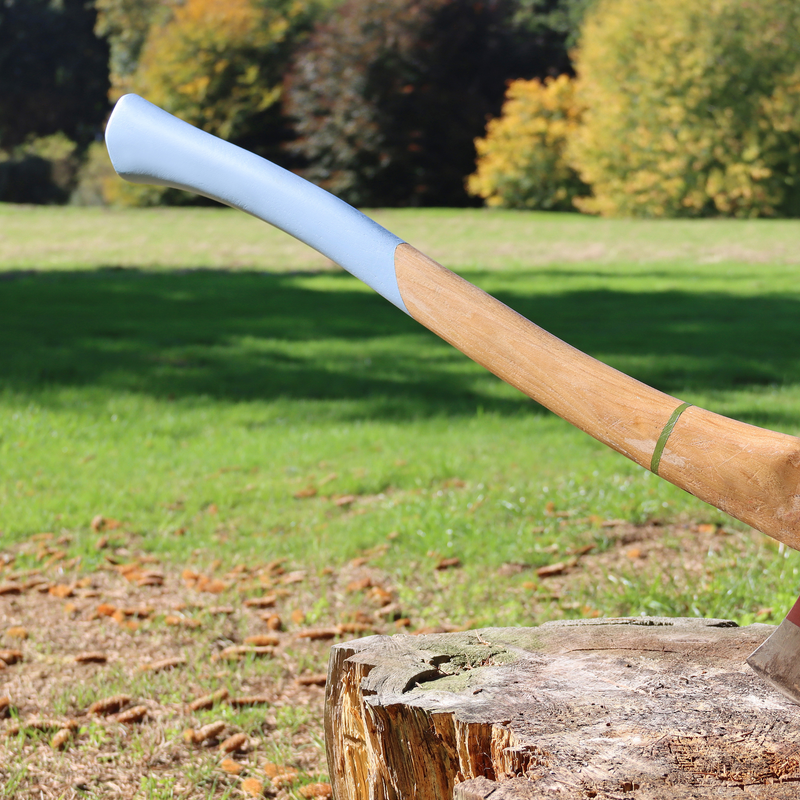 Wooden axe with a blue handle on a log in an outdoor setting