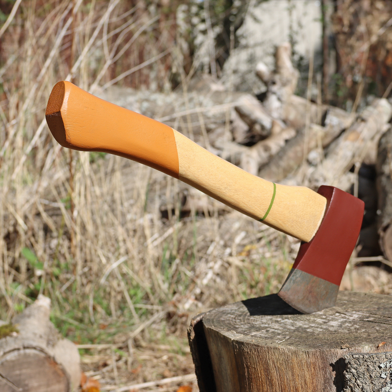 Wooden-handled axe with a red blade on a wooden stump in a forest setting