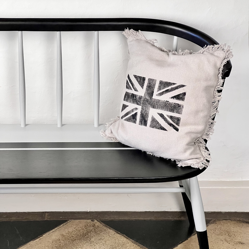 Decorative pillow with a Union Jack design on a black and white bench.