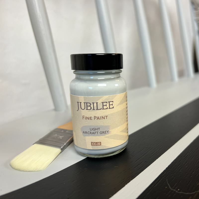 Jubilee Fine Paint jar with a brush on a white surface