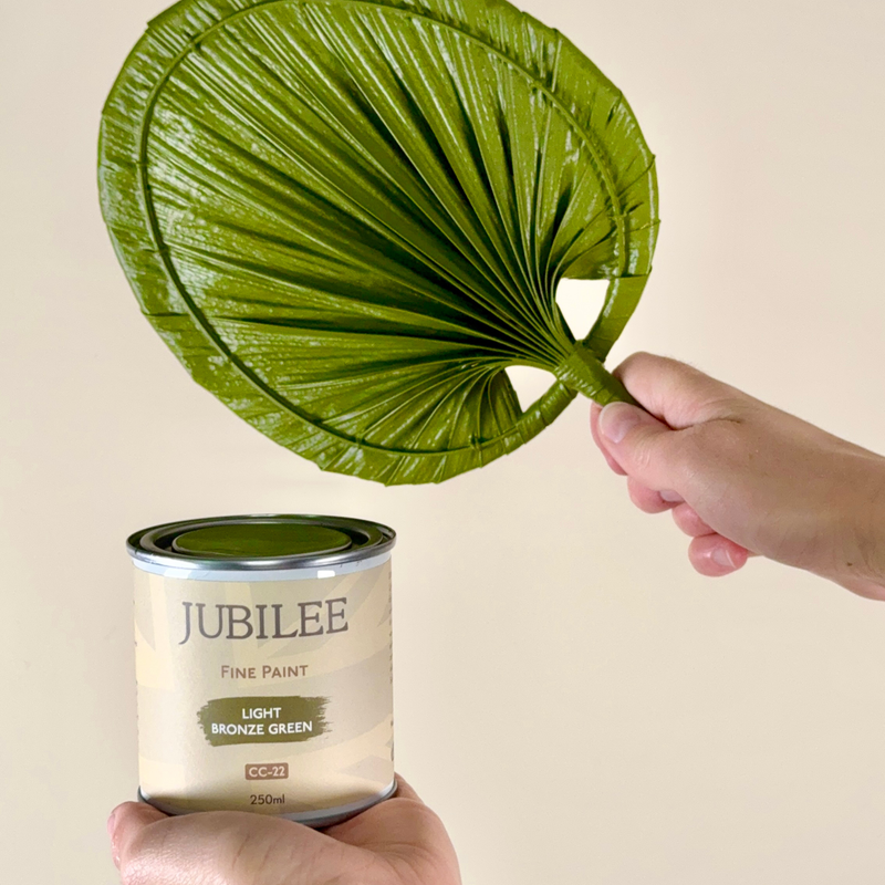 Jubilee paint can with a green leaf against a beige background