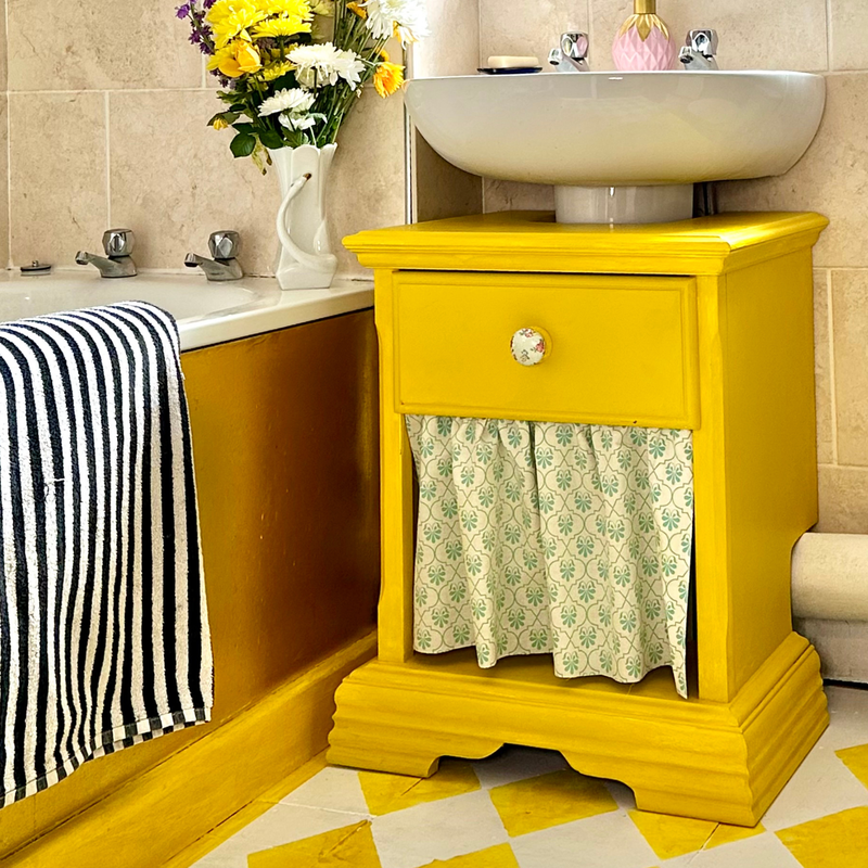 Yellow cabinet with a floral curtain in a bathroom setting