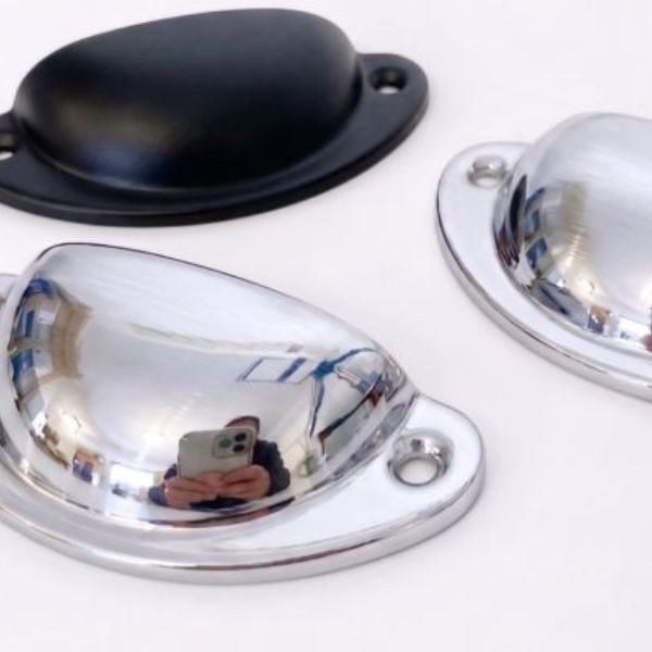 Two dome-shaped metal cabinet knobs with oval bases, one in polished chrome and one in matte black, shown on a white background.