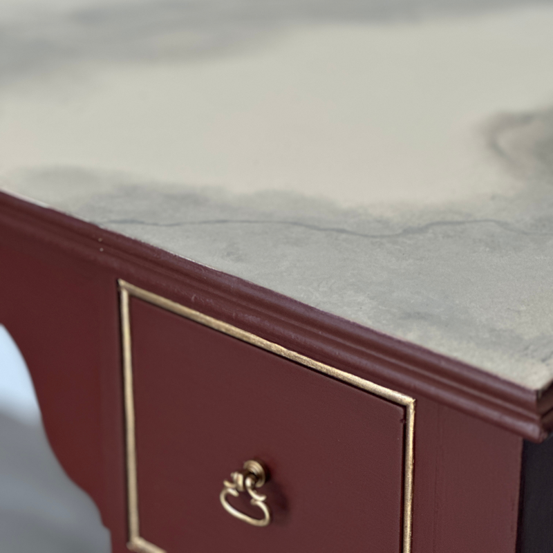 Close-up of a red wooden drawer with a gold handle on a light gray background