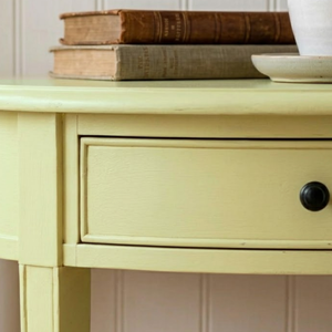 
                      
                        A small baby yellow side table with vintage books on the surface
                      
                    