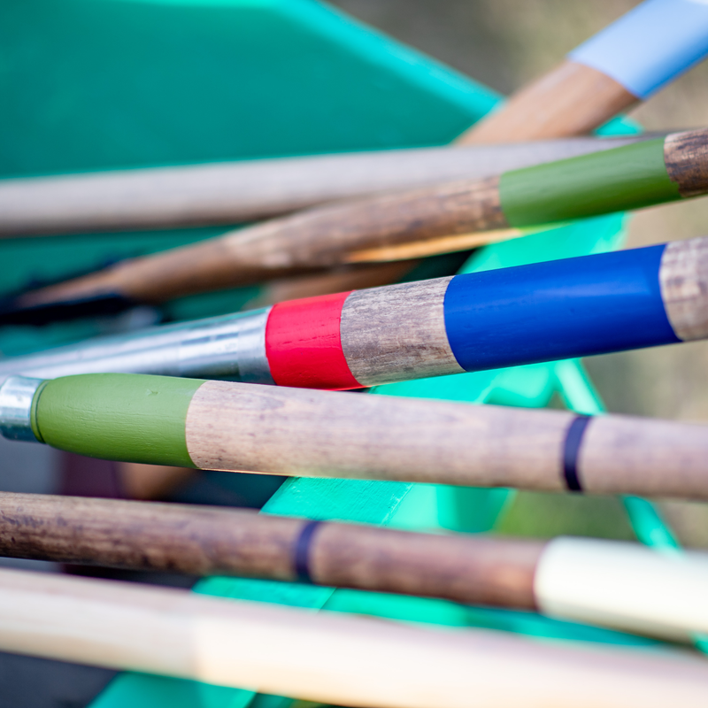 Colourful spade handles with wooden handles and colourful grips on a blurred green background
