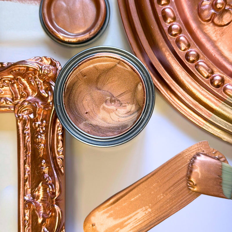 Close-up of a can of bronze paint with decorative elements on a white background