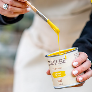 
                      
                        Person pouring yellow paint from a can labeled 'Jubilee' into a container.
                      
                    