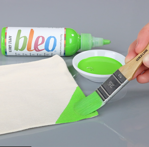 
                      
                        Person using a brush to apply green paint from a bottle labelled 'bleo' onto a white surface.
                      
                    