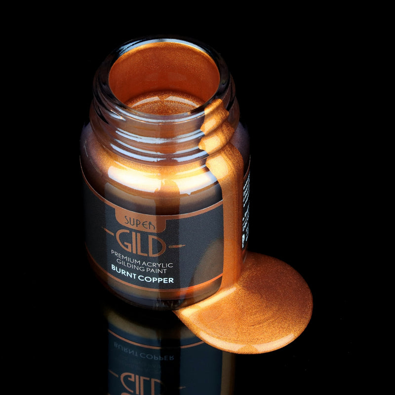 Super GILD Burnt Copper acrylic gilding paint in a jar with metallic paint pooling onto a black background