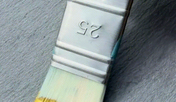 Gif of gold paint brushing across a tile